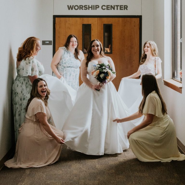 Bride smiling with her bridesmaids while getting ready for her wedding