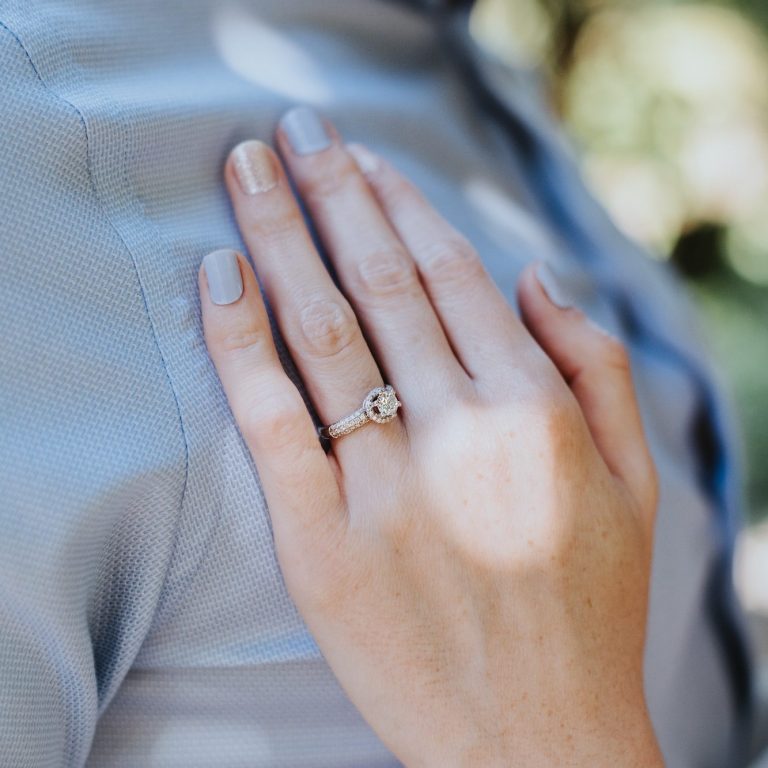 Close-up of a bride’s engagement ring as her hand rests on the groom’s shoulder