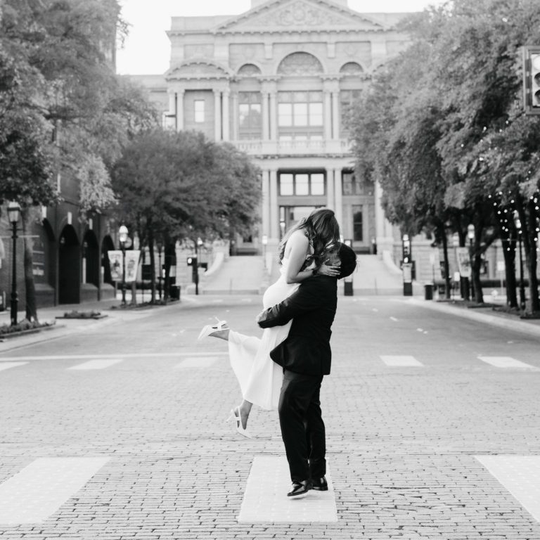 Couple embracing beside historic architecture during a Downtown Fort Worth engagement session