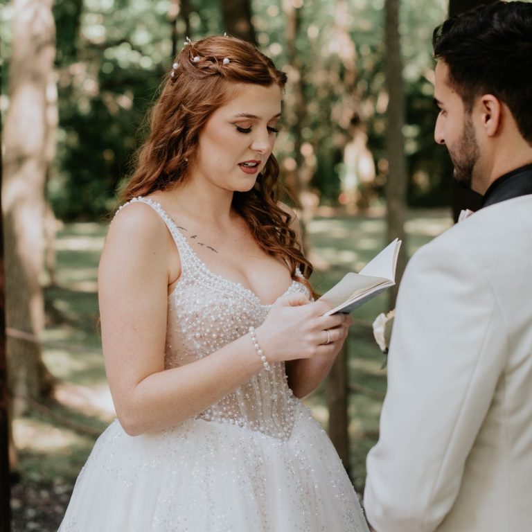 Bride reading a personal letter to the groom during their outdoor wedding ceremony